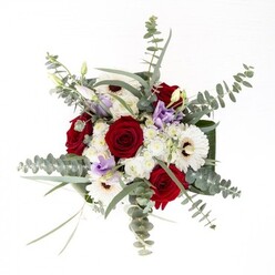 As a florist immersed in Highbury's dynamic rhythms, I view this bouquet as an eloquent dialogue between contrast and cohesion. Creamy white gerberas anchor the arrangement with their sunburst petals and deep brown centers, framed by rich red roses whose swirling shapes evoke timeless love and connection. Wispy eucalyptus floats above, casting delicate, shifting shadows that mirror the dappled light found beneath the trees in Highbury Fields. Among these, dashes of soft lilac lisianthus add a shiver of contemporary flair, like an unexpected breeze through the main square on a late spring afternoon. Cushioning the blooms, fluffy white filler flowers create a sense of gentle fullness. The whole ensemble is gathered by lush, structural foliage and contained in an immaculate glass vase, revealing the green architecture below-stems rising proudly, refreshed daily by Highbury's careful hands. Its layered scent-a blend of rose and cool eucalyptus-invites a long, appreciative inhale. Whether commemorating a cherished date, sending thoughtful comfort, or welcoming someone new to the community, the arrangement embodies the trust and artistry that define our approach at Florist Highbury.